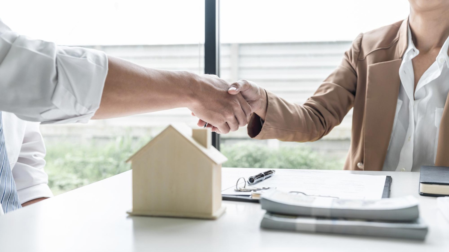 Imagen trayectoria empresarial. Foto cliente y agente inmobiliaria estrechando acuerdo